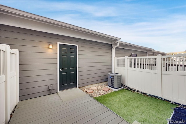 property entrance with fence, a lawn, central AC, and a wooden deck