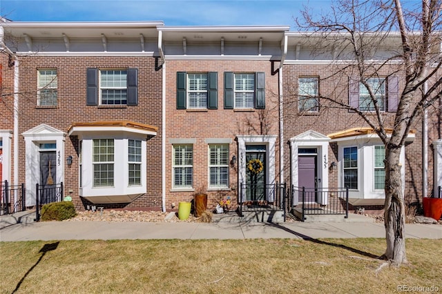 multi unit property featuring brick siding and a front lawn