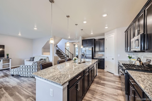 10991 Xanadu St, Commerce City, CO 80022 - kitchen featuring appliances with stainless steel finishes, light wood-style floors, tasteful backsplash, open floor plan, and recessed lighting