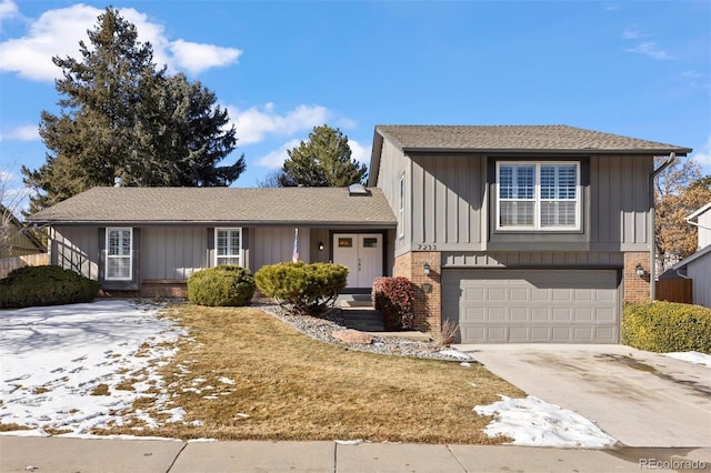 split level home with a garage, board and batten siding, concrete driveway, and brick siding