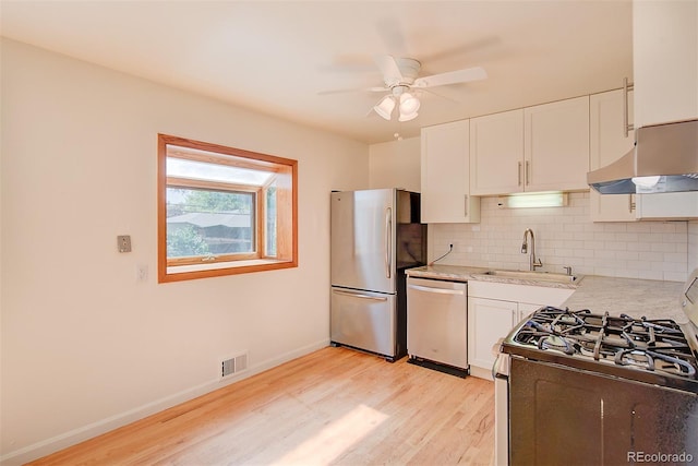 6054 Iris Way, Arvada, CO 80004 - kitchen with appliances with stainless steel finishes, under cabinet range hood, light wood finished floors, a ceiling fan, and backsplash