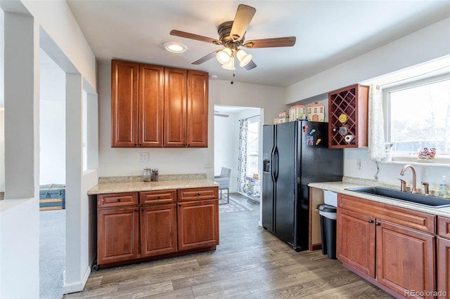 kitchen featuring ceiling fan, black fridge with ice dispenser, sink, and light hardwood / wood-style flooring