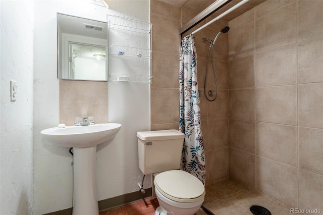 bathroom with sink, curtained shower, and toilet