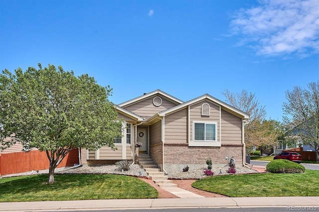 bungalow-style home featuring brick siding, fence, and a front lawn