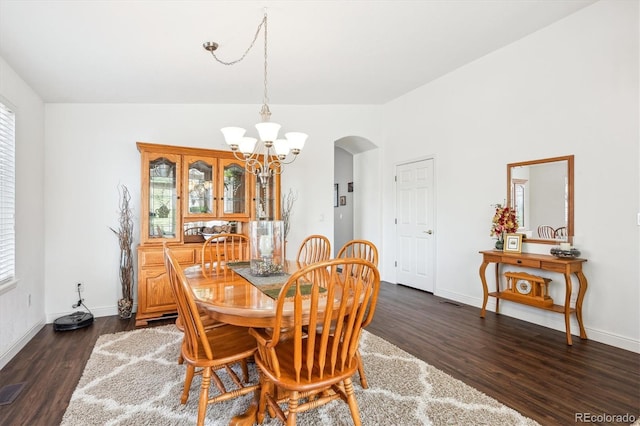dining area featuring an inviting chandelier, arched walkways, dark wood-style flooring, and a wealth of natural light