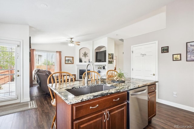 kitchen featuring a fireplace, dishwasher, a sink, baseboards, and dark wood-style floors