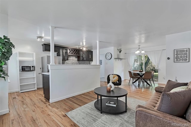 3052 S Grape Way, Denver, CO 80222 - living area with light wood-style floors, ornate columns, and a chandelier