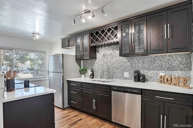 3052 S Grape Way, Denver, CO 80222 - kitchen with stainless steel appliances, decorative backsplash, light countertops, light wood finished floors, and glass insert cabinets