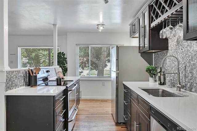 3052 S Grape Way, Denver, CO 80222 - kitchen featuring appliances with stainless steel finishes, backsplash, plenty of natural light, and light wood-style floors