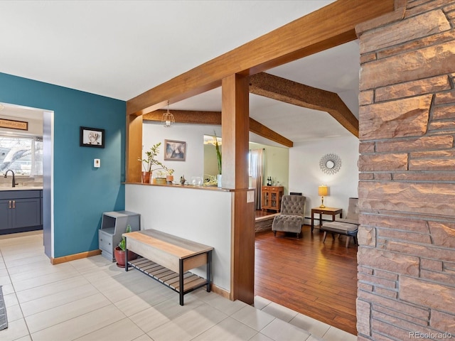 hallway with beam ceiling, baseboard heating, sink, and light tile patterned floors