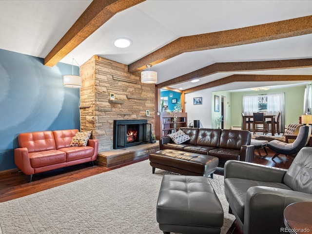 living room featuring baseboard heating, a stone fireplace, vaulted ceiling with beams, and dark hardwood / wood-style floors