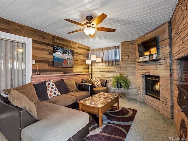 carpeted living room with a fireplace, wood walls, and ceiling fan