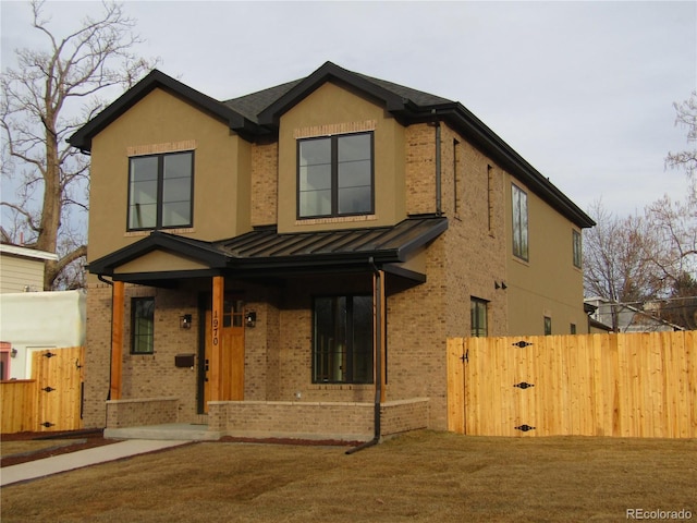 view of front of home featuring brick siding, a standing seam roof, a gate, fence, and metal roof