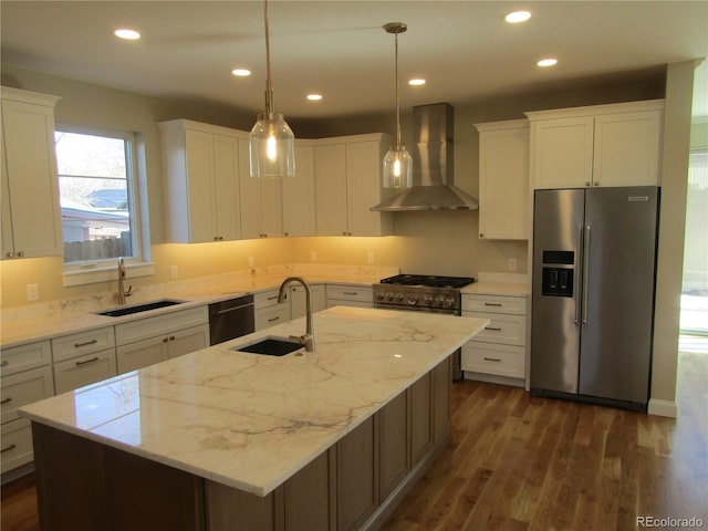 kitchen with stainless steel appliances, wall chimney exhaust hood, a sink, and white cabinets