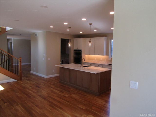 kitchen with double oven, recessed lighting, dark wood-type flooring, a sink, and white cabinets