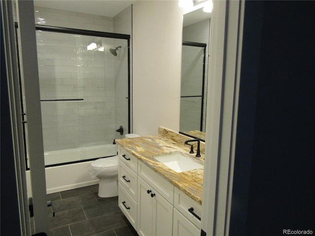 bathroom featuring enclosed tub / shower combo, vanity, toilet, and tile patterned floors