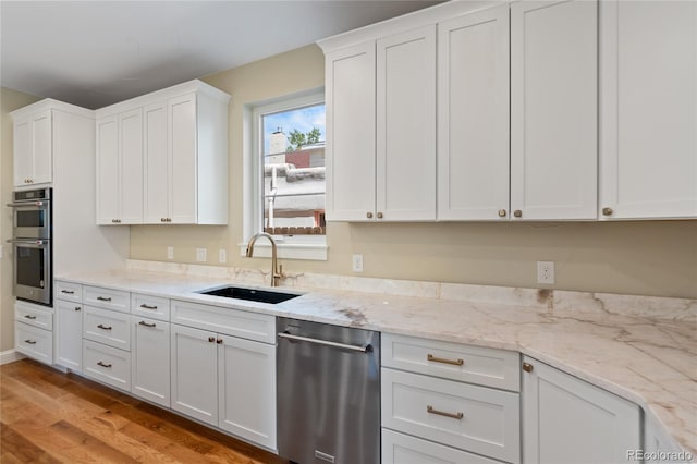 1970 S Logan St, Denver, CO 80210 - kitchen featuring a sink, appliances with stainless steel finishes, white cabinetry, light wood-style flooring, and light stone countertops