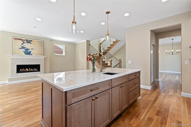 1970 S Logan St, Denver, CO 80210 - kitchen with a sink, light wood-style flooring, a fireplace, light stone countertops, and baseboards