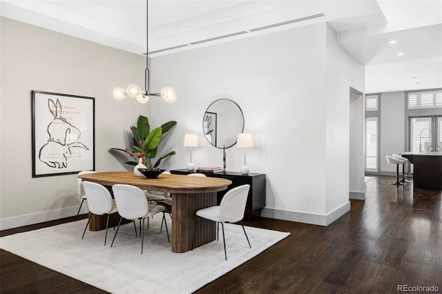 dining room with dark wood-type flooring and an inviting chandelier