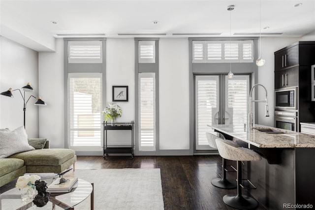 living room with dark wood-type flooring, a towering ceiling, and sink