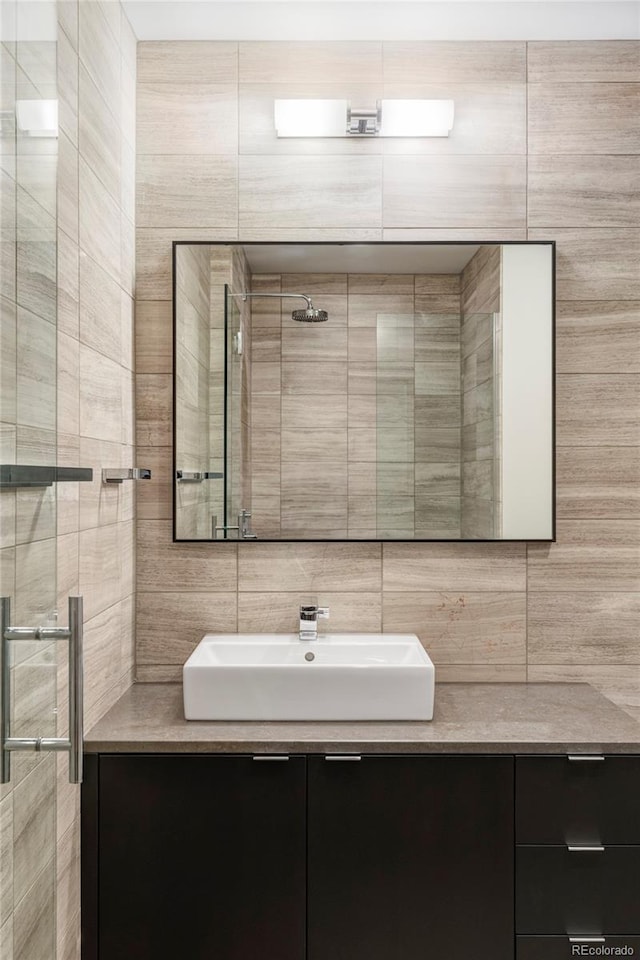 bathroom with a shower, tile walls, and vanity