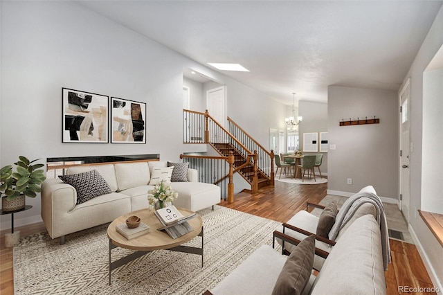 13849 W 66th Dr, Arvada, CO 80004 - living area featuring a chandelier, wood finished floors, stairs, lofted ceiling, and a skylight