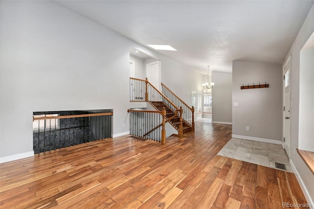 13849 W 66th Dr, Arvada, CO 80004 - spare room featuring a chandelier, wood finished floors, stairs, a skylight, and lofted ceiling