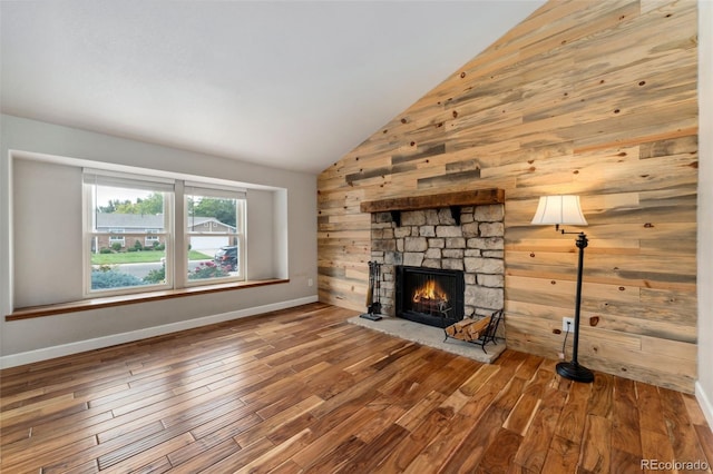 13849 W 66th Dr, Arvada, CO 80004 - unfurnished living room featuring a stone fireplace, wooden walls, wood finished floors, and high vaulted ceiling