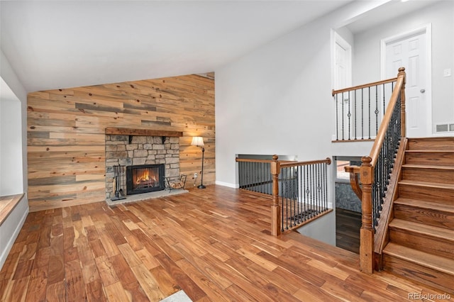 13849 W 66th Dr, Arvada, CO 80004 - unfurnished living room with lofted ceiling, wooden walls, wood finished floors, and a fireplace