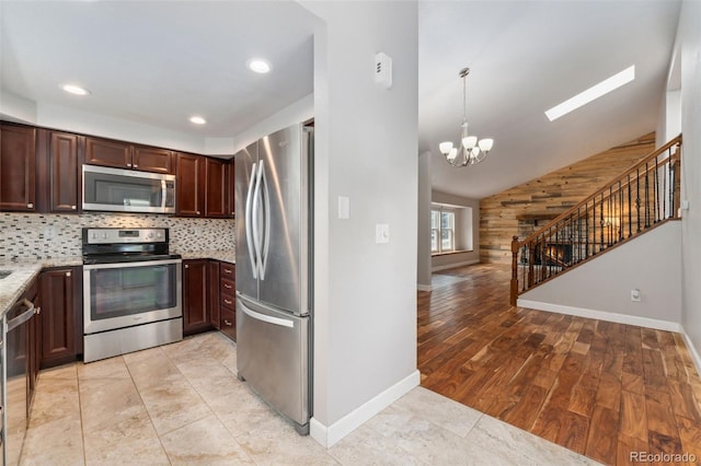 13849 W 66th Dr, Arvada, CO 80004 - kitchen featuring appliances with stainless steel finishes, a chandelier, vaulted ceiling, light stone countertops, and decorative backsplash