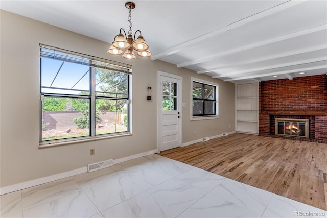 10851 E Iliff Pl, Aurora, CO 80014 - unfurnished living room featuring beamed ceiling, a chandelier, a brick fireplace, and built in shelves