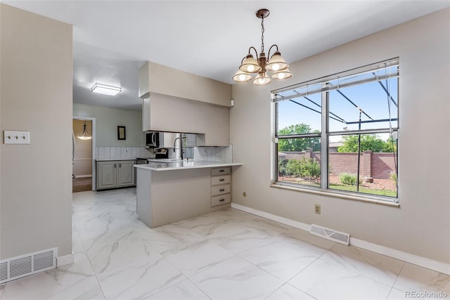 10851 E Iliff Pl, Aurora, CO 80014 - kitchen featuring light marble finish flooring, a peninsula, a chandelier, light countertops, and hanging light fixtures