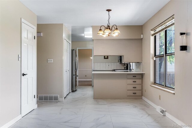 10851 E Iliff Pl, Aurora, CO 80014 - kitchen with light marble finish flooring, a peninsula, freestanding refrigerator, a chandelier, and backsplash