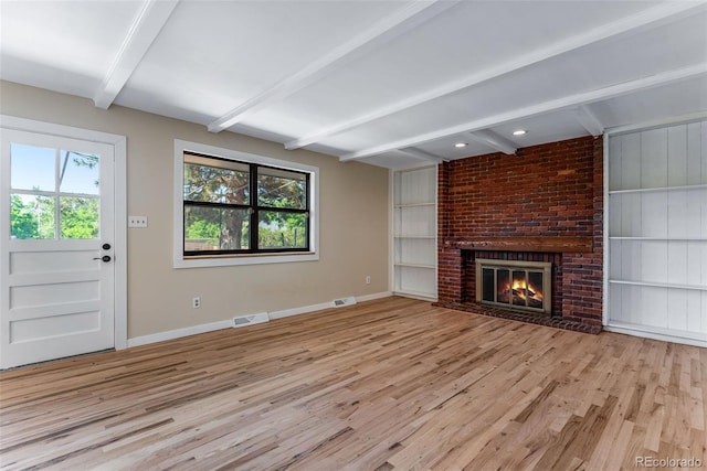 10851 E Iliff Pl, Aurora, CO 80014 - unfurnished living room with wood finished floors, beam ceiling, a fireplace, and built in shelves