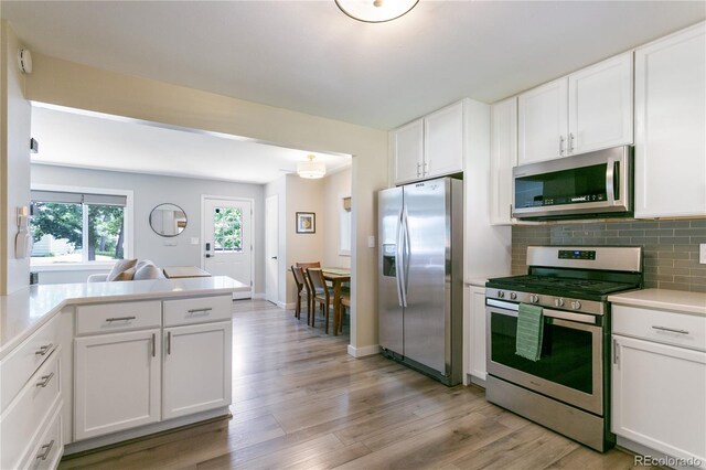 5280 S Logan St, Littleton, CO 80121 - kitchen with appliances with stainless steel finishes, light wood-style flooring, light countertops, white cabinetry, and tasteful backsplash