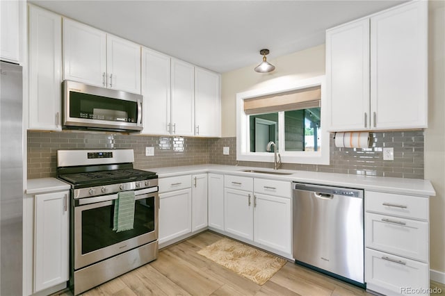 5280 S Logan St, Littleton, CO 80121 - kitchen with stainless steel appliances, light countertops, light wood finished floors, white cabinetry, and decorative backsplash