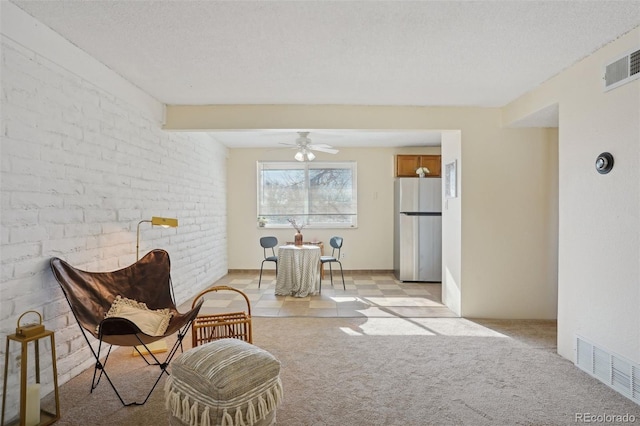 sitting room with light carpet, a textured ceiling, and ceiling fan