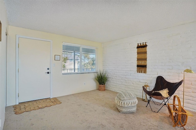 unfurnished room featuring a textured ceiling, carpet floors, and brick wall