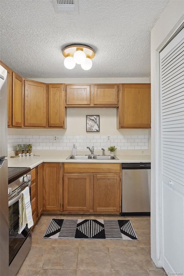 kitchen featuring decorative backsplash, sink, a textured ceiling, and appliances with stainless steel finishes