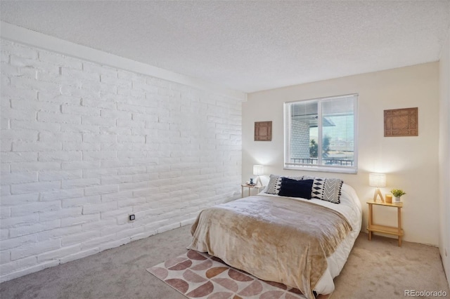 bedroom featuring light carpet, a textured ceiling, and brick wall