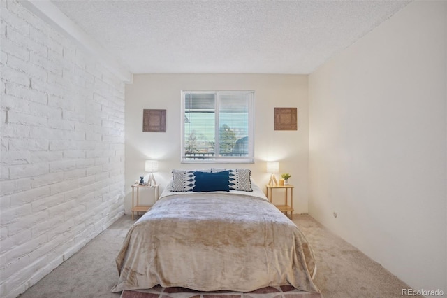 bedroom featuring carpet floors, a textured ceiling, and brick wall