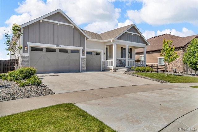 23913 E Swallow Cir, Aurora, CO 80016 - craftsman house with board and batten siding, a porch, a garage, concrete driveway, and stone siding