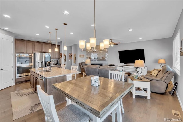 23913 E Swallow Cir, Aurora, CO 80016 - dining area with wood finished floors, recessed lighting, ceiling fan, a chandelier, and a fireplace