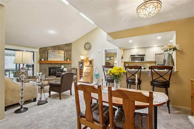 dining space with light carpet, a fireplace, baseboards, and lofted ceiling