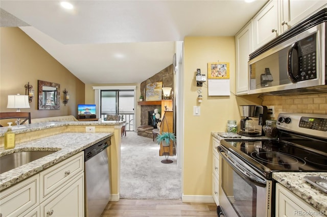 kitchen featuring stainless steel appliances, light wood-style floors, light stone countertops, decorative backsplash, and open floor plan