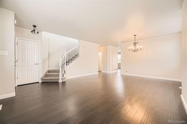 unfurnished living room with a chandelier, stairway, dark wood-type flooring, and baseboards