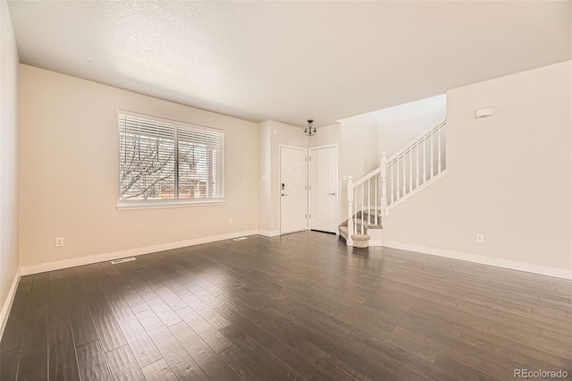 unfurnished living room with stairway, baseboards, dark wood-type flooring, and a textured ceiling