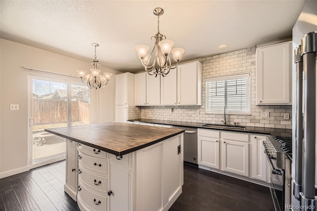 kitchen with backsplash, wooden counters, a chandelier, white cabinets, and a sink