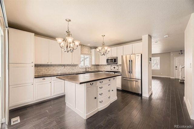 kitchen featuring wooden counters, dark wood-type flooring, a chandelier, stainless steel appliances, and a sink