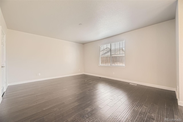 unfurnished room with dark wood-type flooring, baseboards, and a textured ceiling